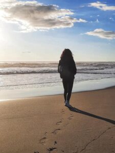 Camminata meditativa, donna cammina sulla spiaggia