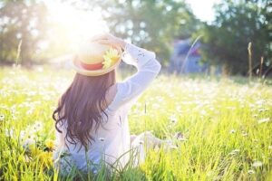 Primavera, donna seduta in un campo fiorito