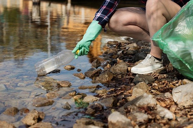 Plogging, ragazza raccoglie rifiuti da un torrente